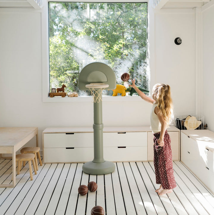 Mom and child shooting hoops at the palm green hoop in a sunny playroom