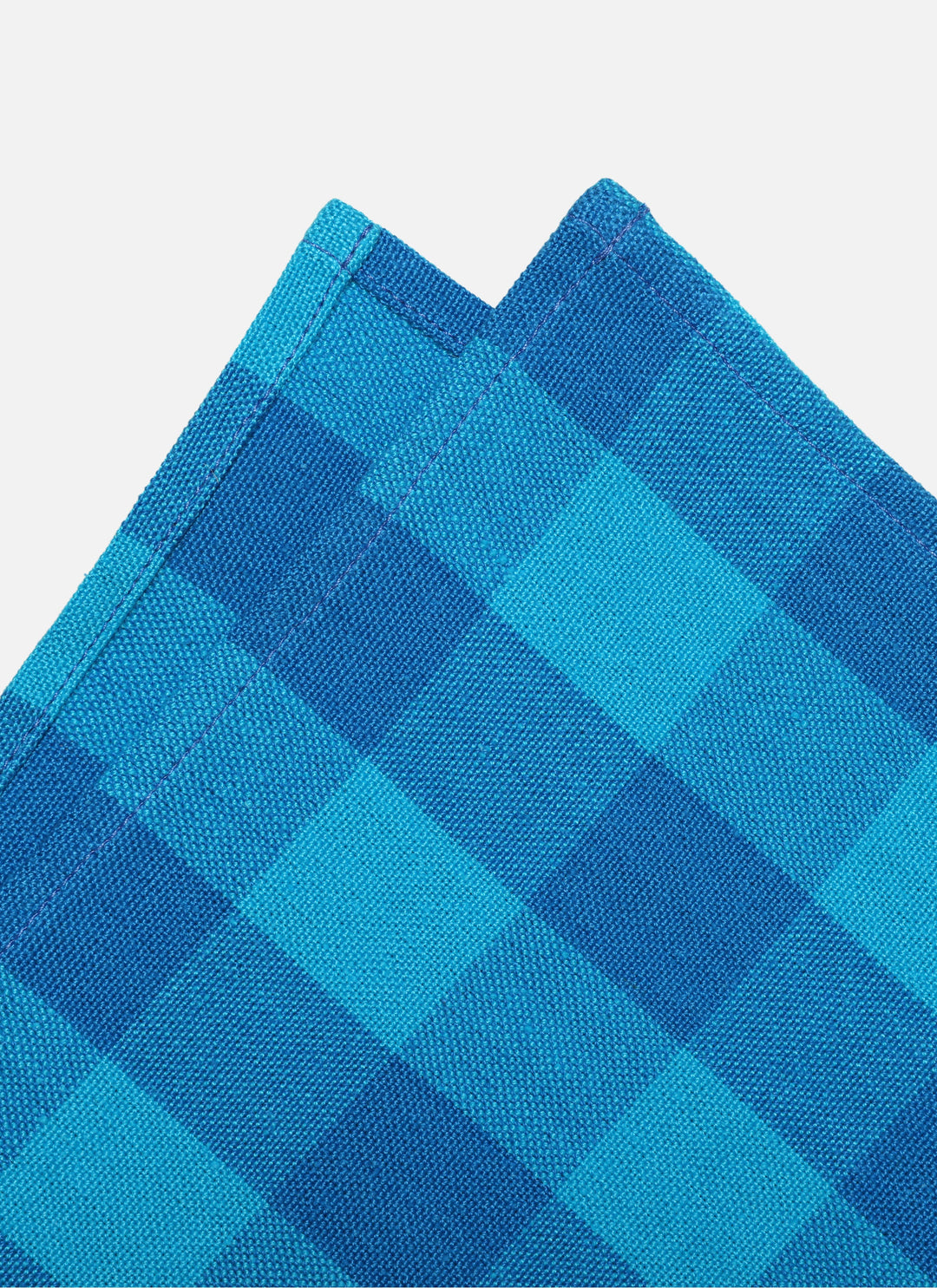 Close-up of the two-tone turquoise gingham weave on the folded cotton napkin