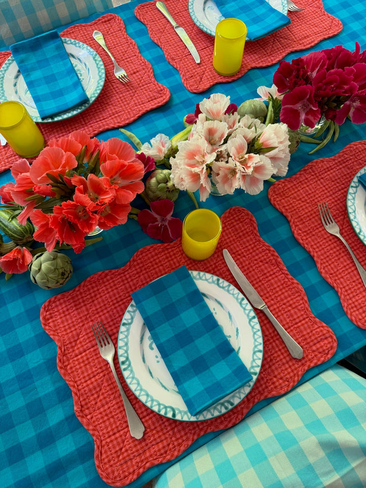 Turquoise gingham napkin at a poolside place setting with blue and white plates