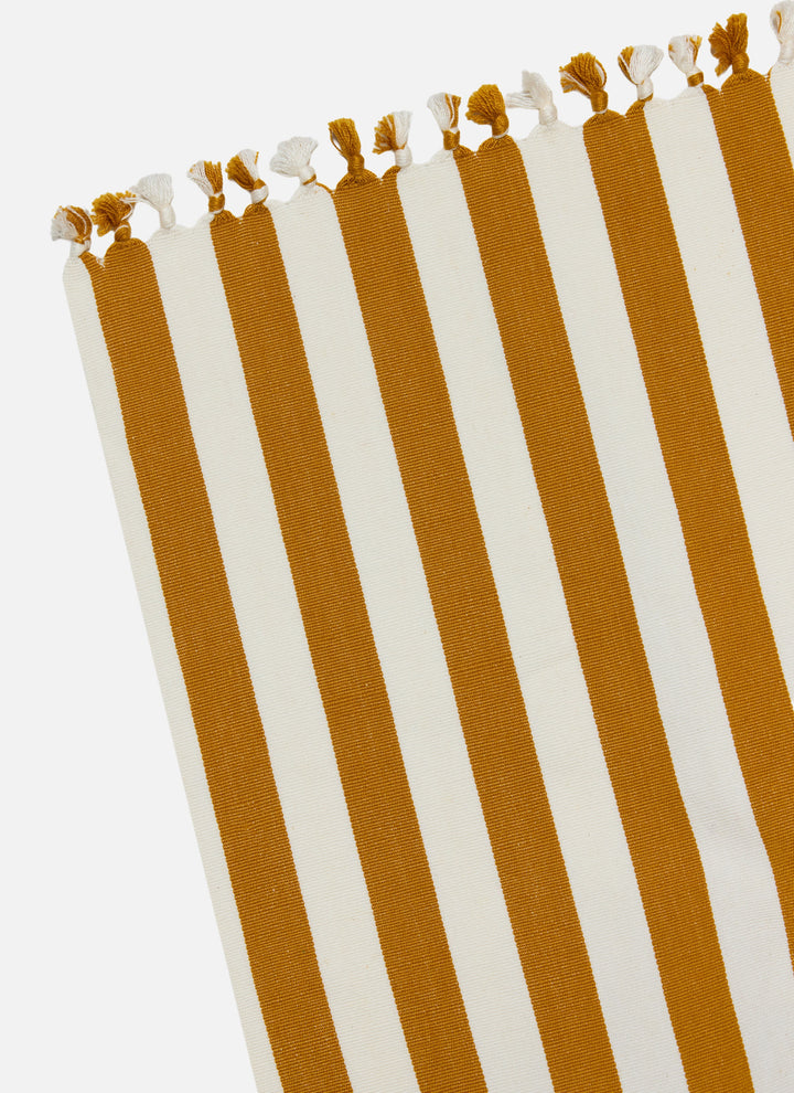 Corner of the goldenrod stripe tablecloth showing the cream tassel trim up close