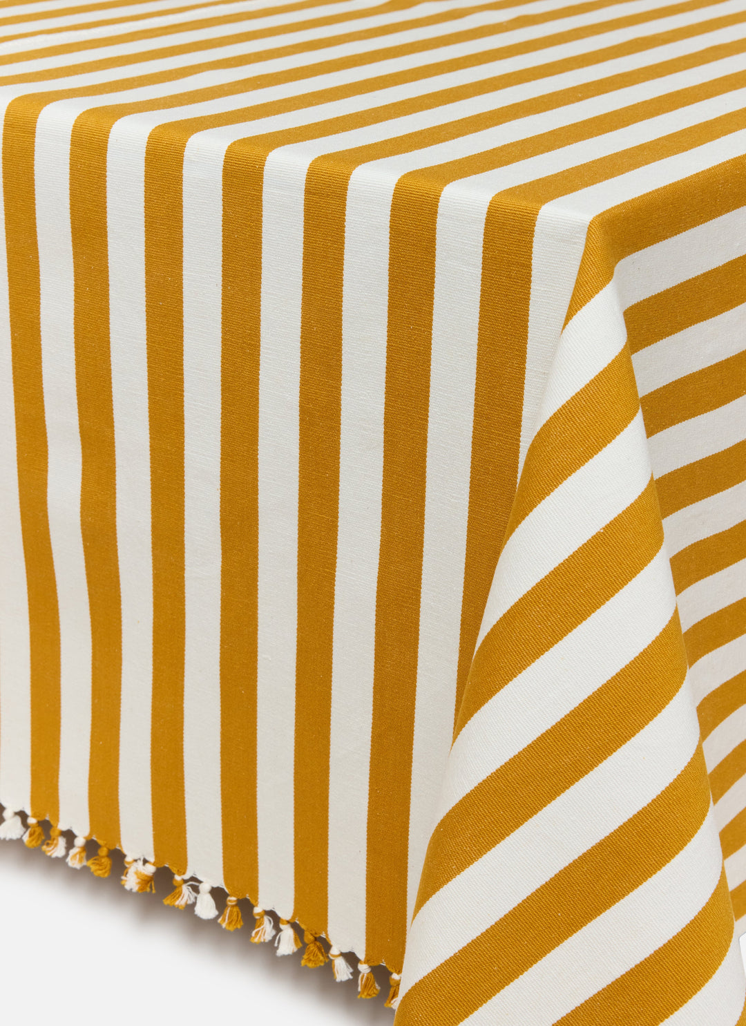 Goldenrod and cream stripe tablecloth draped over a table showing the knotted tassel edge