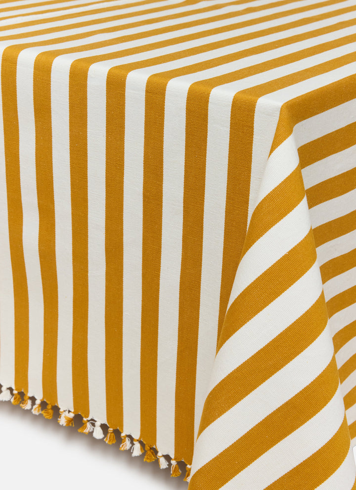 Goldenrod and cream stripe tablecloth draped over a table showing the knotted tassel edge