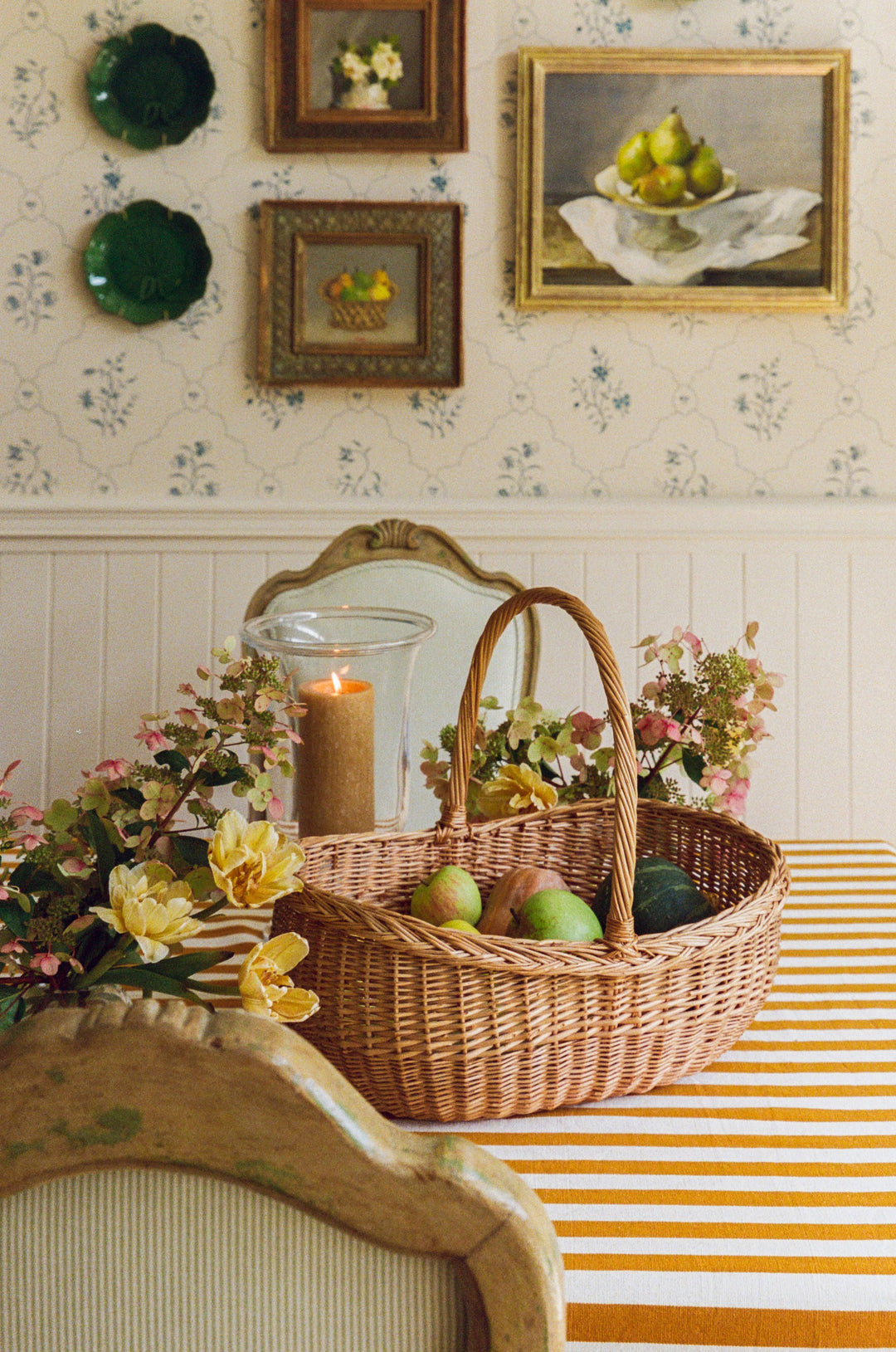 Goldenrod stripe tablecloth with a basket of green apples, a candle, and blossom branches