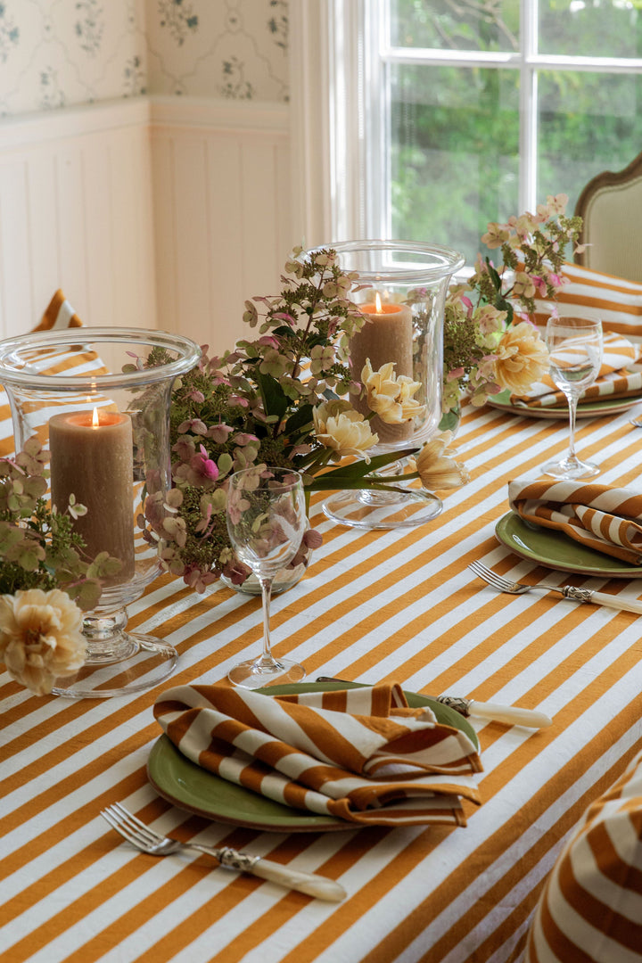 Goldenrod stripe napkins and tablecloth set for a fall dinner with candles and flowers