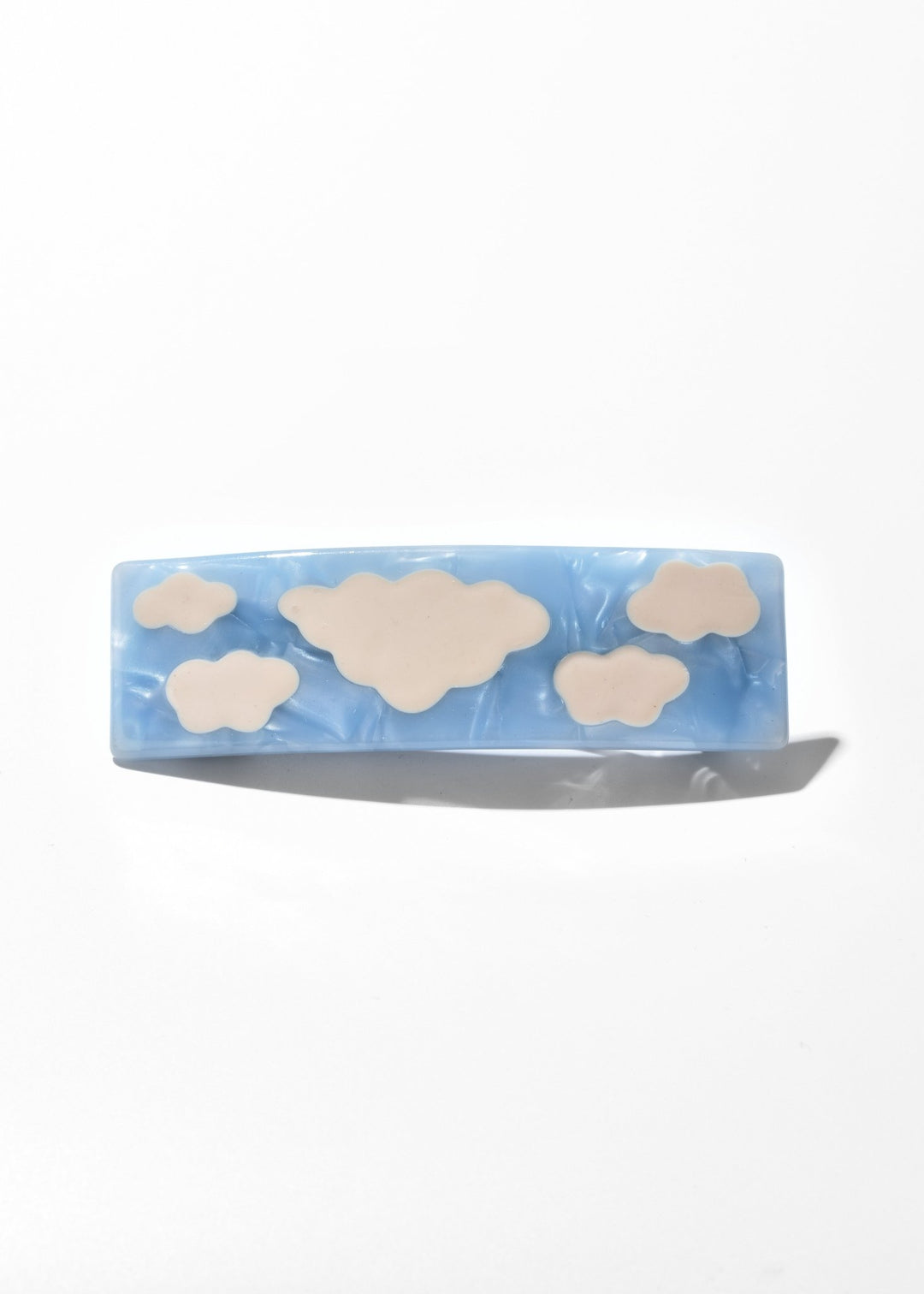 Blue acrylic cloud hair clip with cream cloud inlays on a white background
