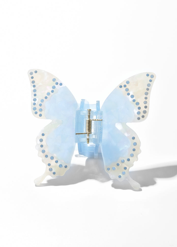 Blue iridescent acrylic butterfly claw clip with dotted wing edges on a white background
