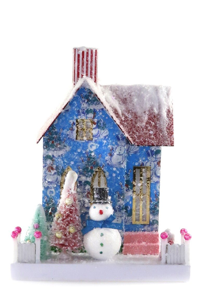 Blue snowman-print Christmas village house with red glitter snowy roof, striped chimney, top-hat snowman, and pink tree