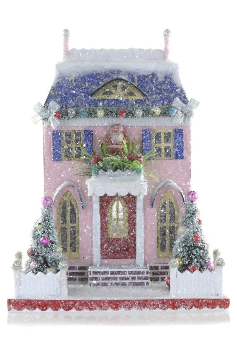 Pink and blue glitter paper Christmas cottage with arched windows and snowy bottle brush trees for a holiday village display