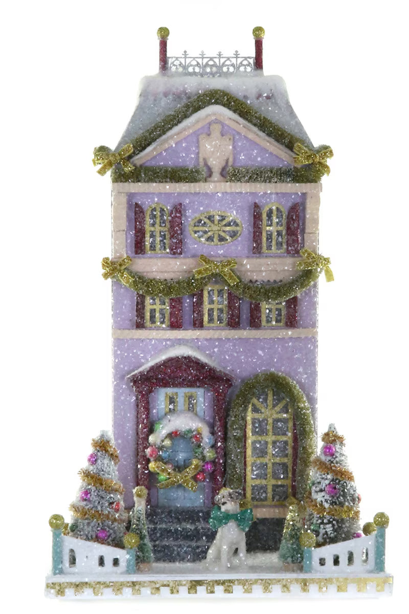 Lavender glitter paper Christmas townhouse with garlands, a wreath, and bottle brush trees for holiday mantel decor