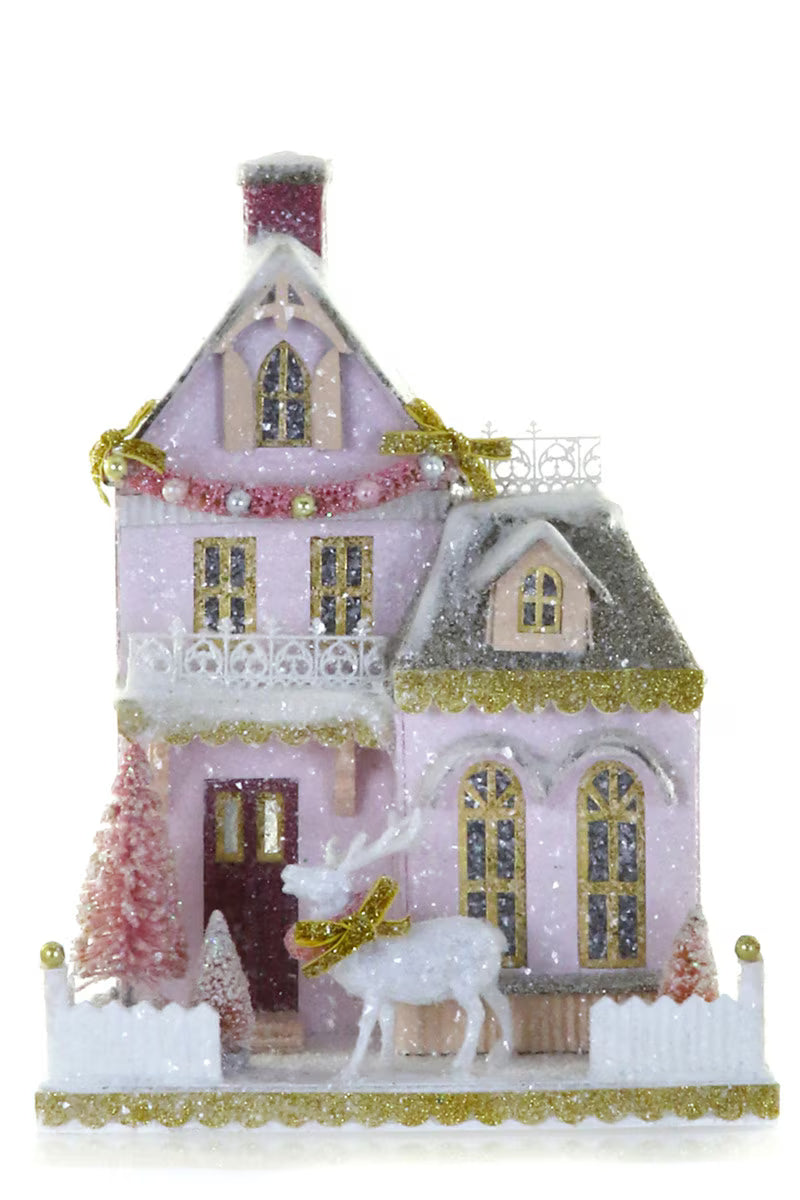Pink glitter paper Christmas house with balconies, a white deer, and pink bottle brush trees for holiday mantel decor