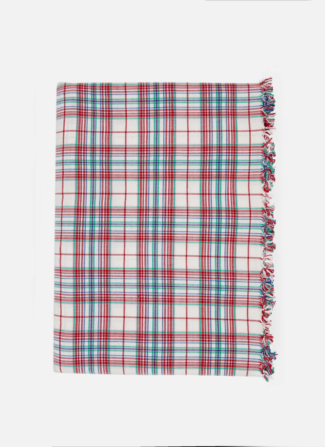 Long table in a Clara plaid tablecloth set with candles and red flowers by a window