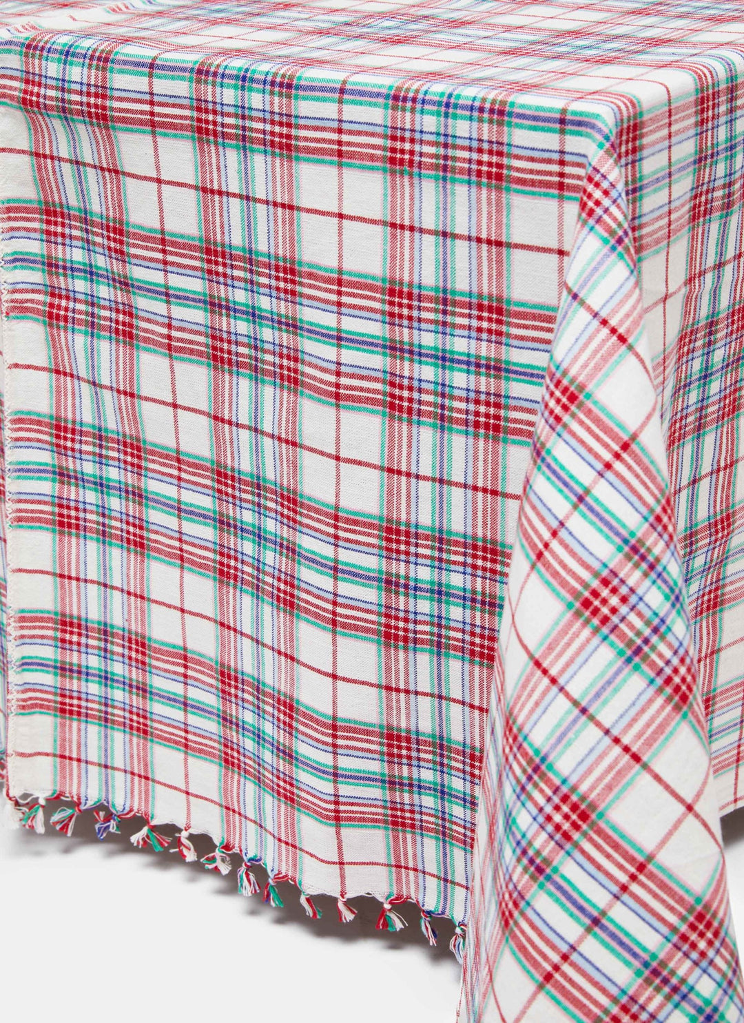 Clara plaid tablecloth on a dining table with candles, red flowers, and black bentwood chairs
