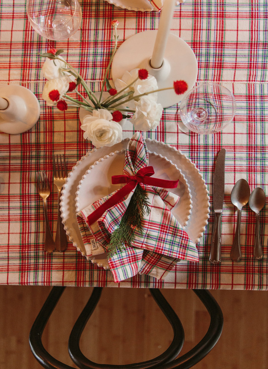 Christmas place setting with a Clara plaid napkin, beaded plates, candles, and red berries
