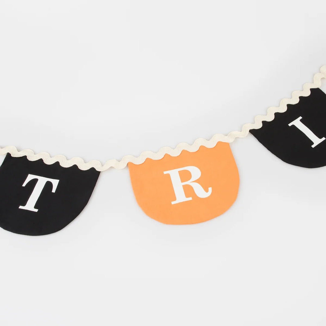 Trick or treat Halloween garland detail with black and orange scalloped fabric pennants on cream ric rac cord