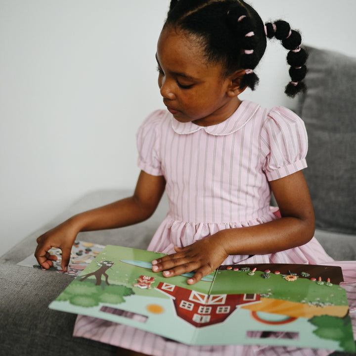 Child playing with a Mushie reusable sticker book