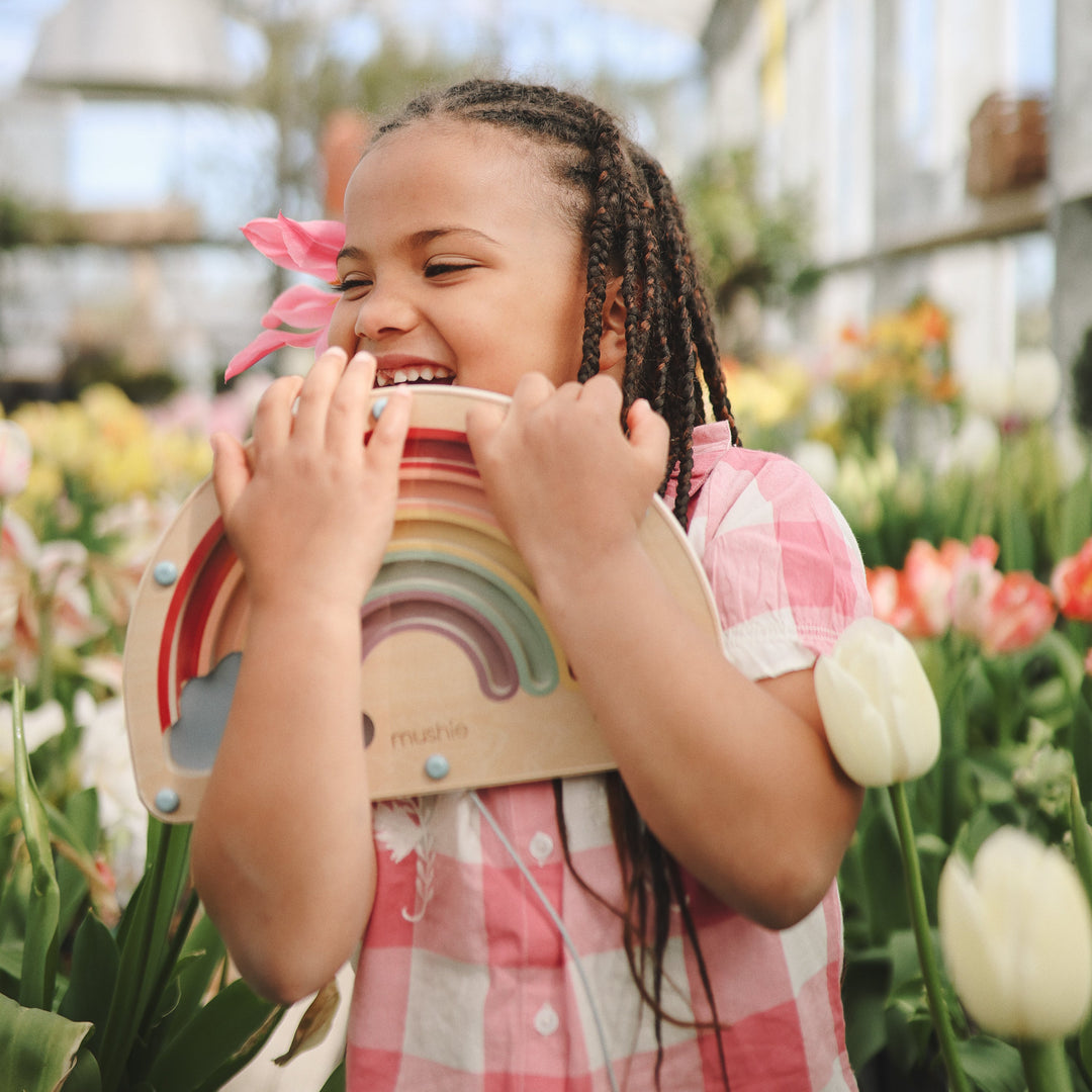 Child playing with the Mushie wooden magnetic rainbow maze