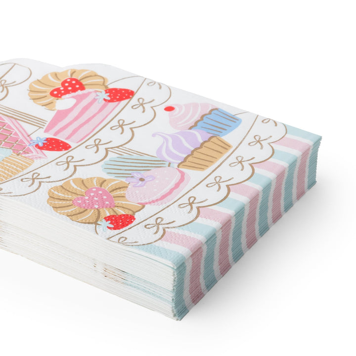 A stack of decorative paper napkins featuring a pastel cupcake and dessert illustration on top, with pink, blue, and white striped edges, photographed on a clean white background.