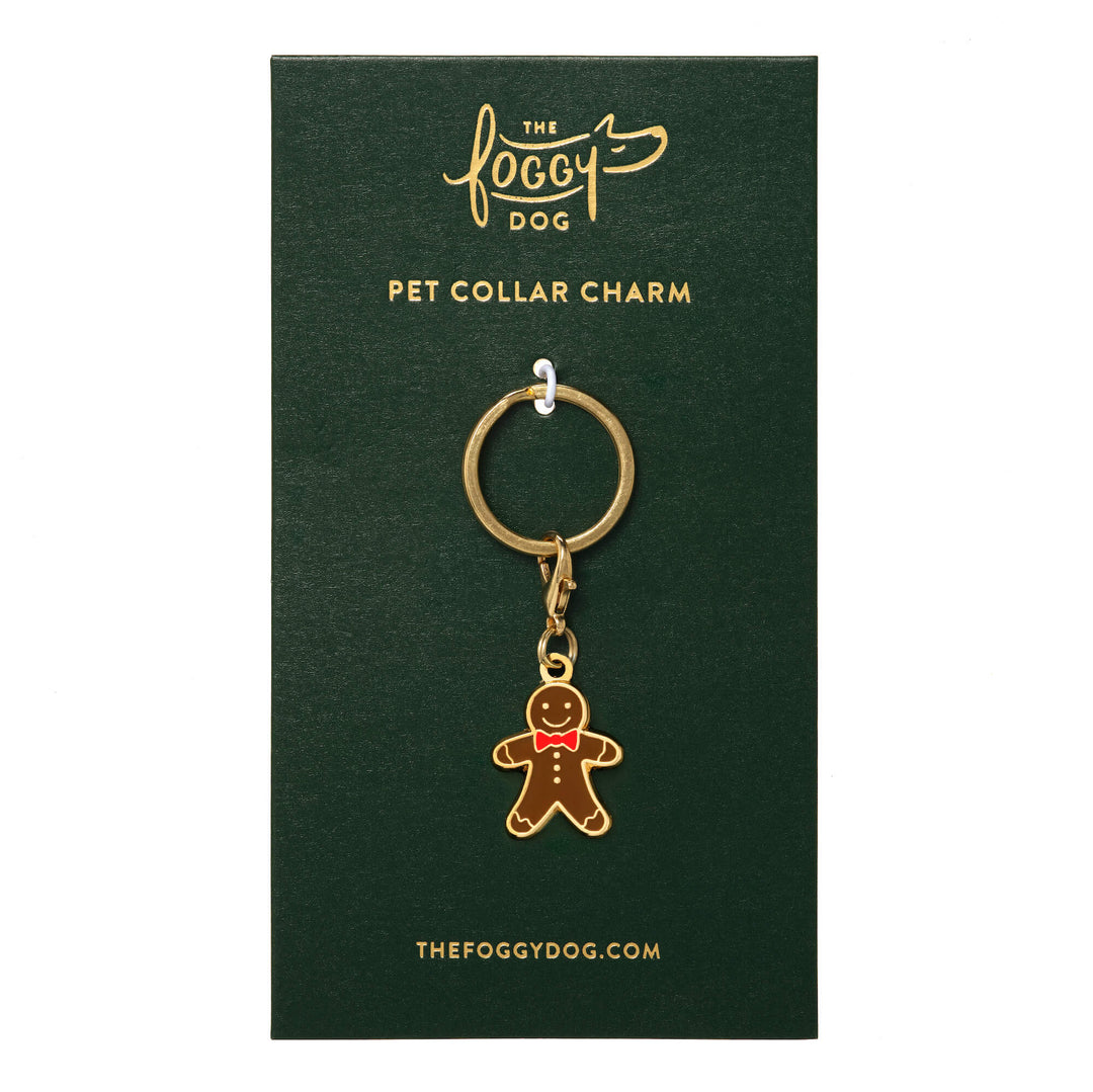 Gingerbread man collar charm with a red bow tie and gold hardware mounted on a green Foggy Dog backing card.