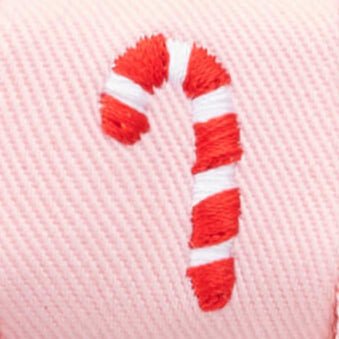 Macro of a single candy cane embroidered in red and white on pink twill
