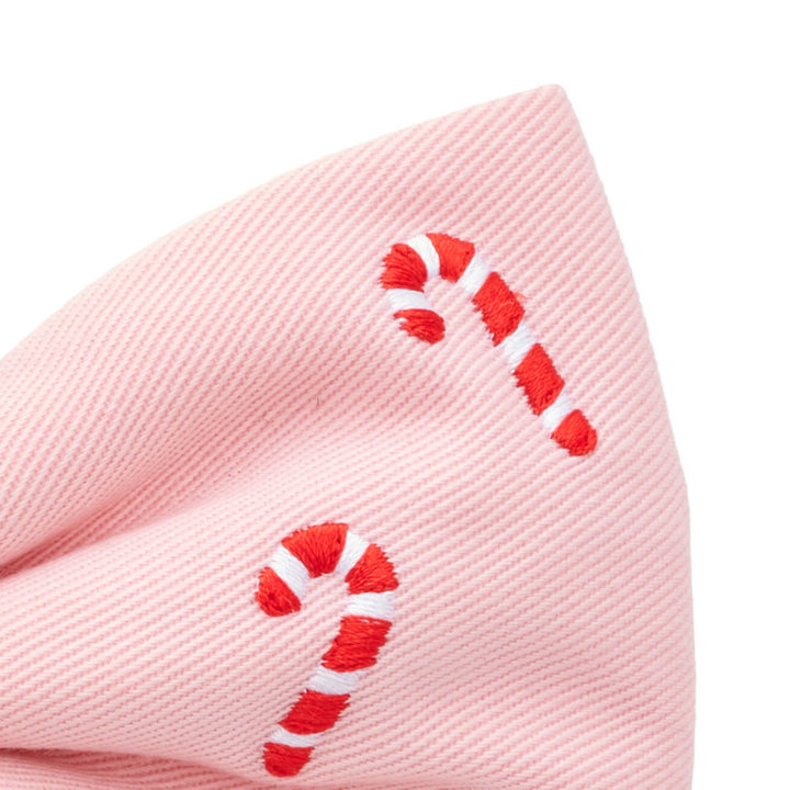Close-up of one blush pink bow tail with two embroidered red and white candy canes