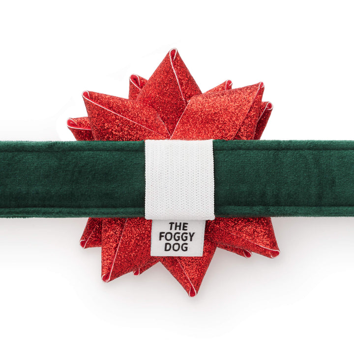 Back of the red glitter gift bow showing its white elastic loop securing it to the green velvet dog collar.