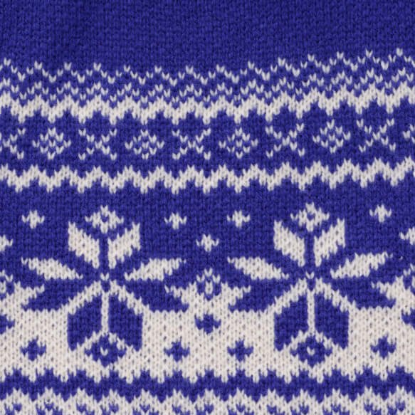 Close-up of cream snowflakes and Fair Isle bands knitted into cobalt blue sweater fabric.