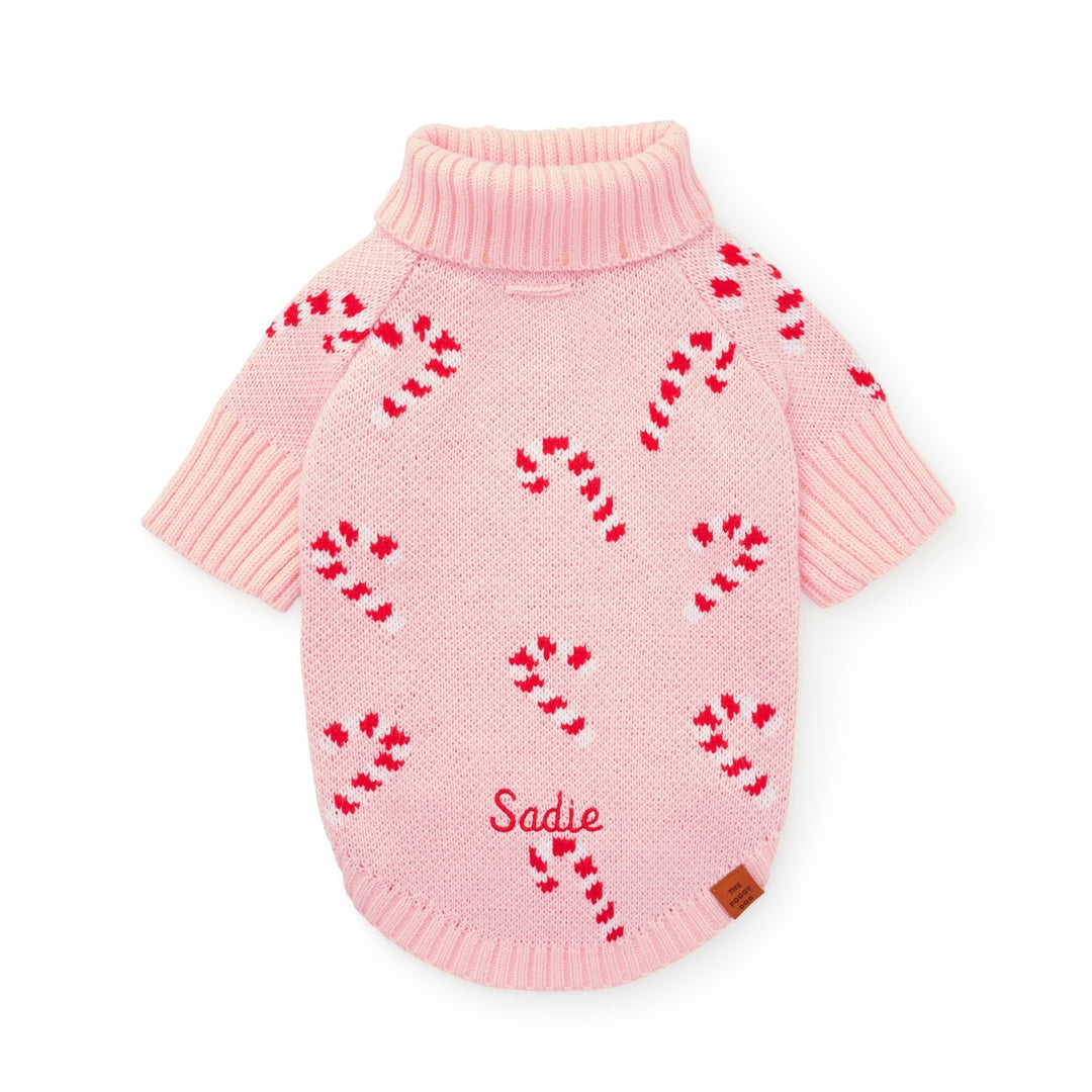 Pink candy cane sweater flat from the back with a sample name stitched in red near the hem