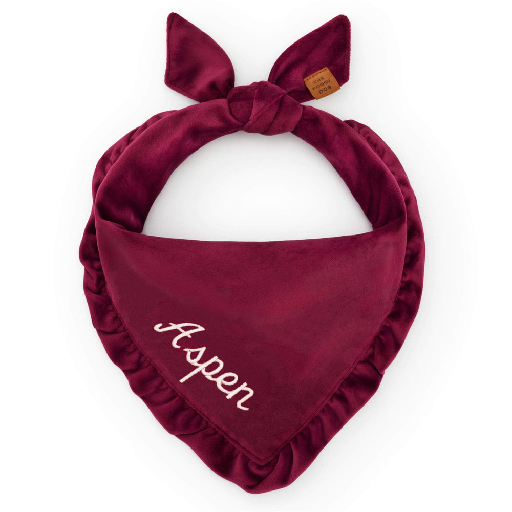 Burgundy velvet ruffled bandana tied on white, a sample name stitched in cream script