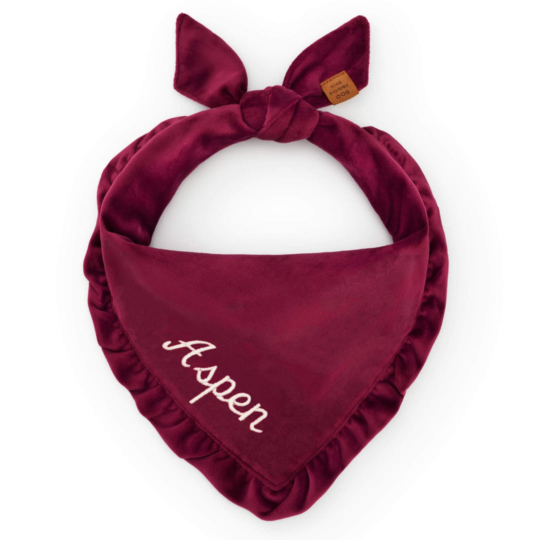 Burgundy velvet ruffled bandana tied on white, a sample name stitched in cream script
