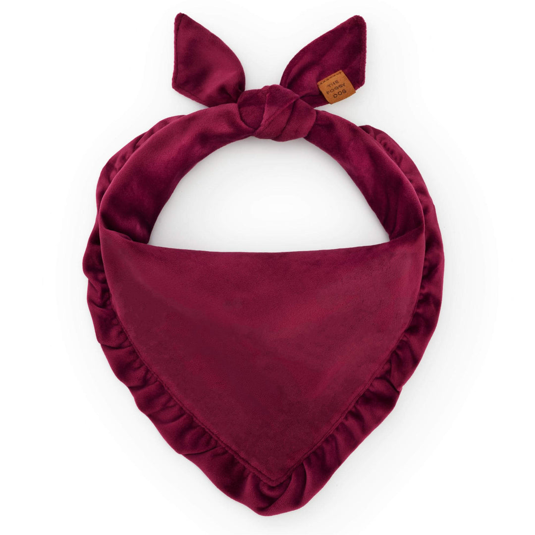 Burgundy velvet ruffled dog bandana tied in a loop on white with a leather tag at the knot