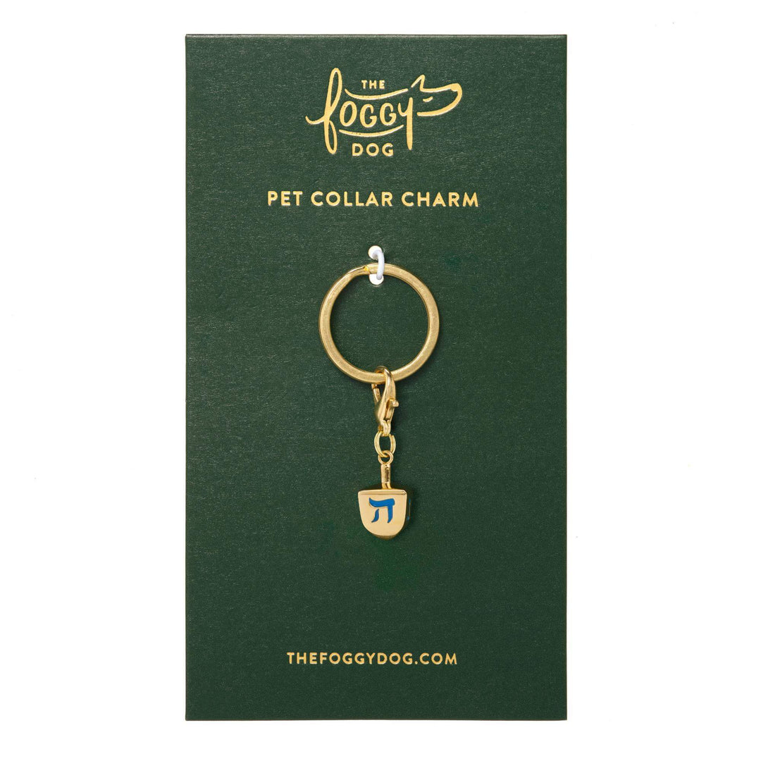 Dreidel collar charm clipped to its green The Foggy Dog pet collar charm backer card