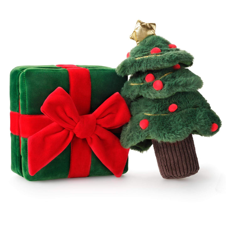 Green present with red bow and fuzzy Christmas tree dog toys side by side on white
