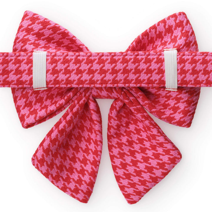 Back of the pink and red houndstooth sailor bow showing two white elastic loops securing it to the matching collar.
