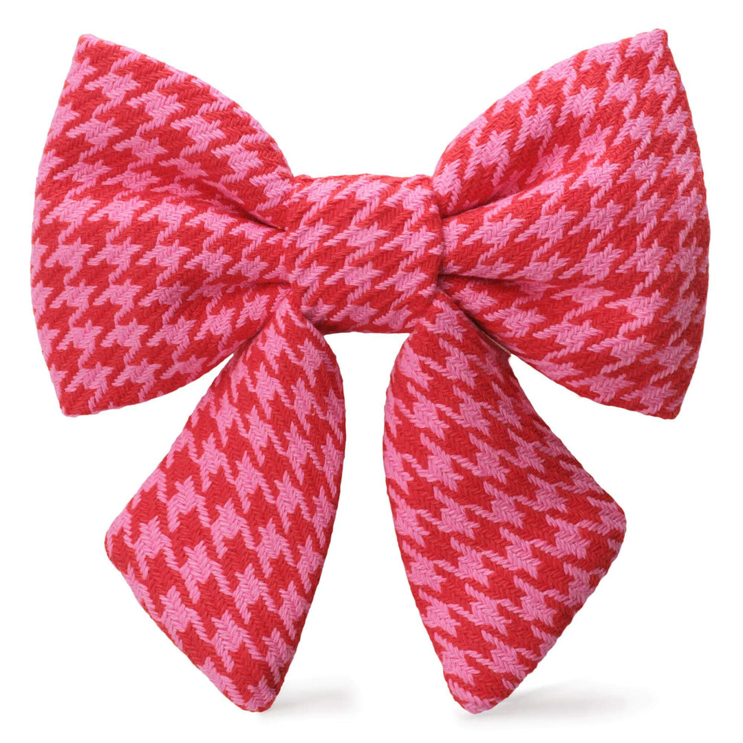 Pink and red houndstooth sailor dog bow with two tapered tails on white.