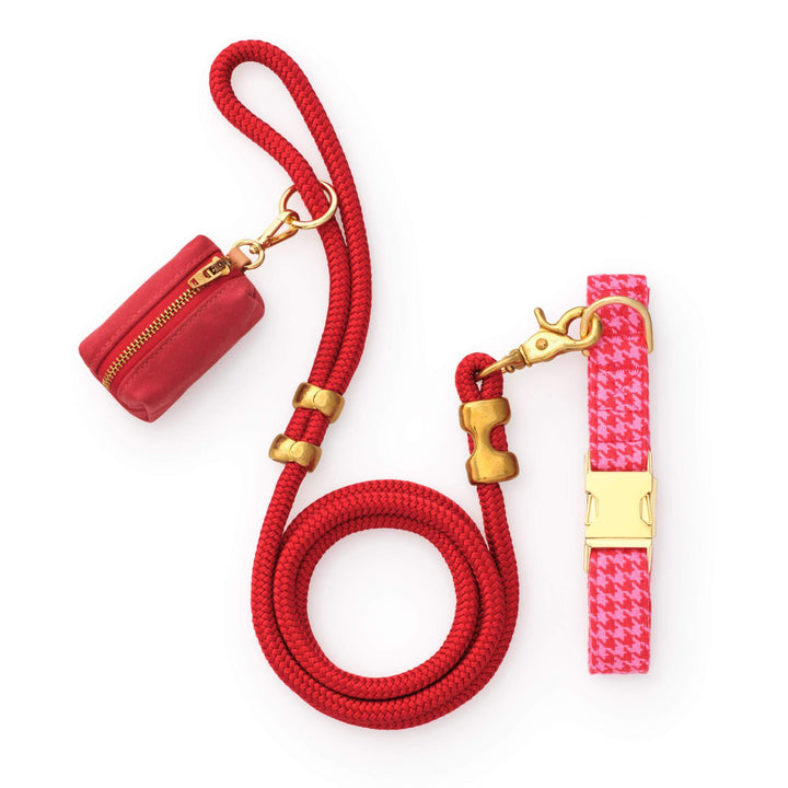 Red rope leash, red waxed canvas bag holder, and pink and red houndstooth collar on white