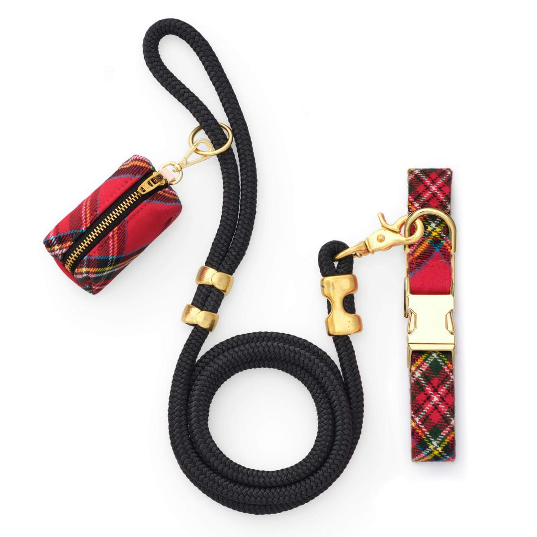 Red tartan collar and matching bag holder beside a coiled black rope leash with gold hardware on white.