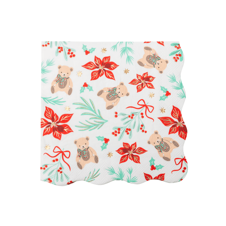 A square white paper napkin with a scalloped edge, featuring a festive Christmas pattern of teddy bears, red poinsettias, green pine branches, holly leaves, and red berries on a white background.