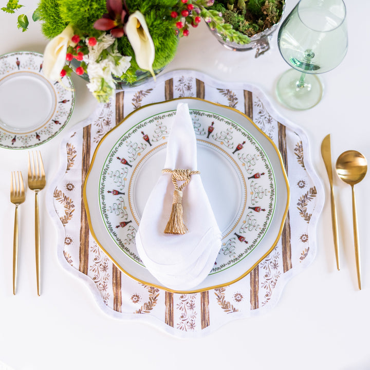 Boxwood Garden espresso placemat styled in a place setting with a gold-rimmed floral plate, gold flatware, and a green glass goblet