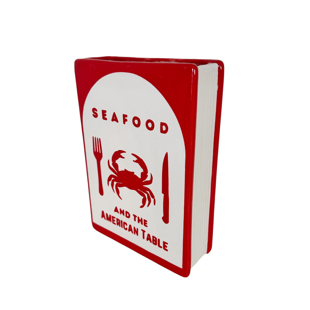 Red and white book titled 'Seafood and the American Table' with a crab illustration on a white background