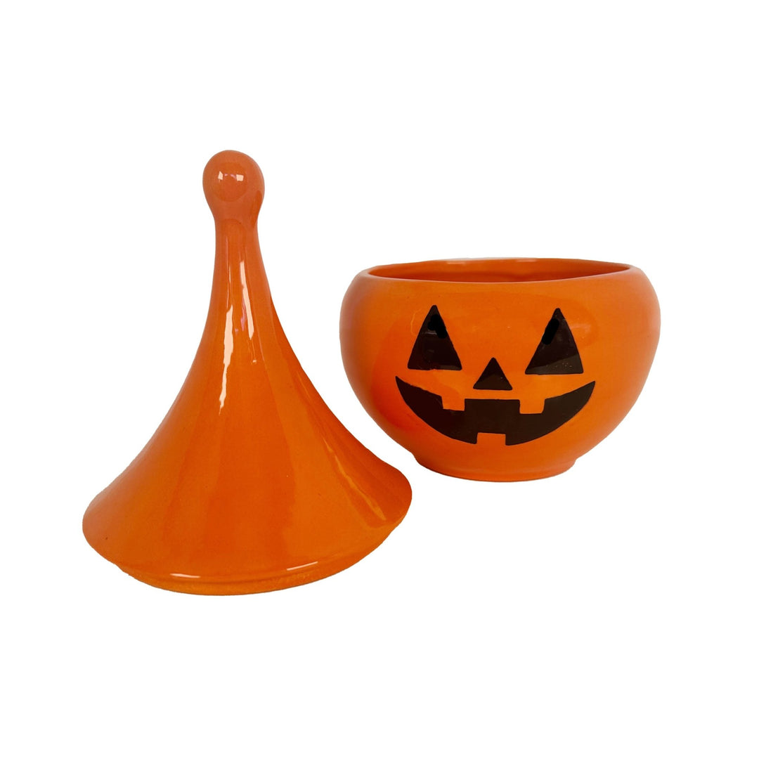 Orange ceramic jar with a pointed lid and another jar with a jack-o'-lantern face design on a white background.