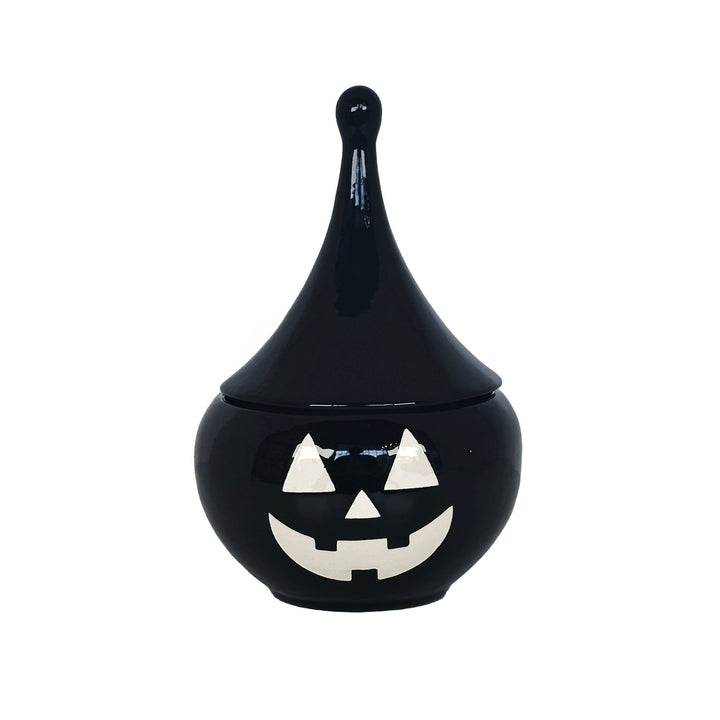 Black ceramic jar with a jack-o'-lantern face on a white background