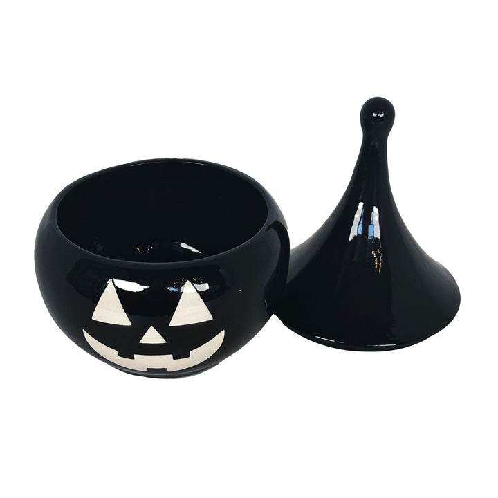 Black ceramic pumpkin with a face design on a white background