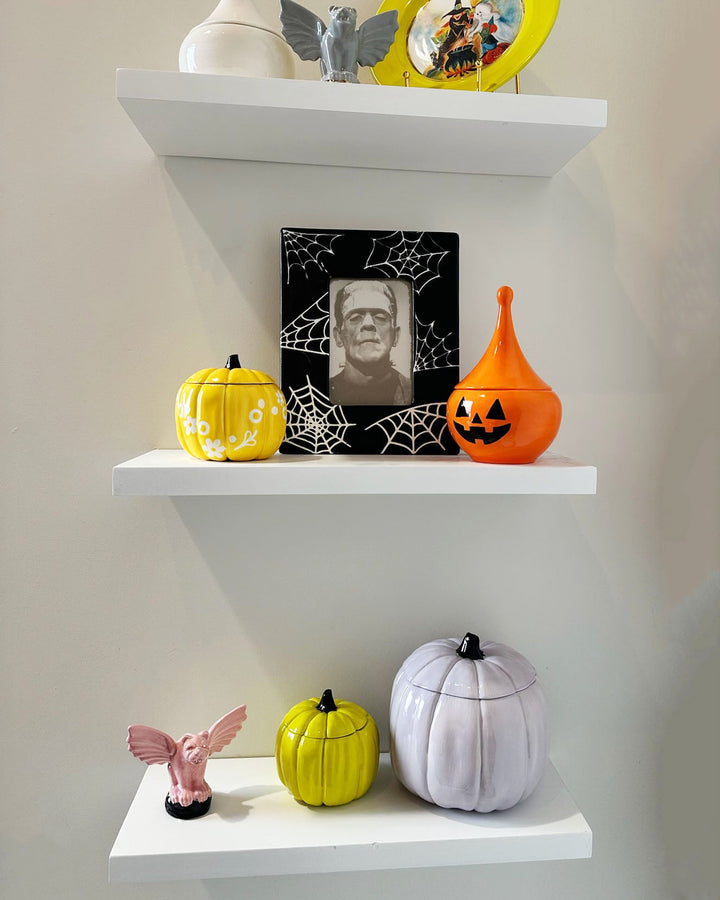Decorative shelves with Halloween-themed items including pumpkins and a portrait of a man.