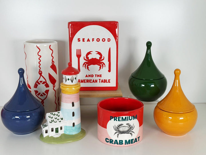 Collection of ceramic items including jars and a sign with a crab design on a white background
