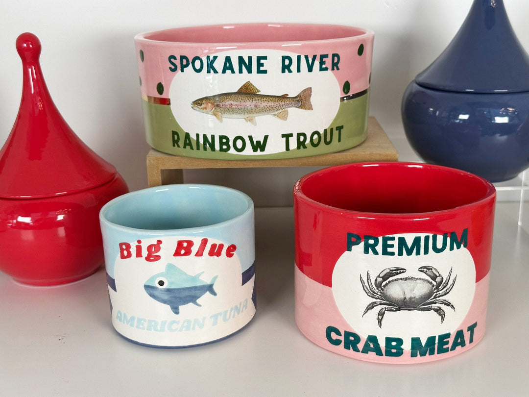 Crab meat can vase grouped with trout and tuna can pottery and red and blue lidded jars for a seaside dinner party