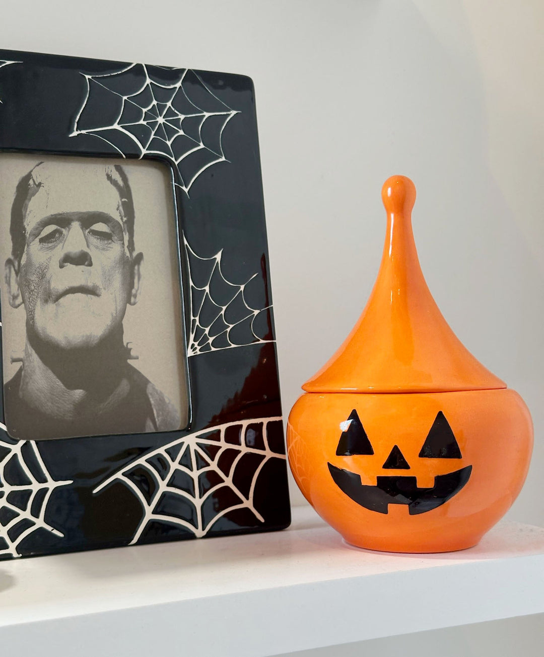 Halloween-themed decorative item with Frankenstein's monster picture and orange jack-o'-lantern container.