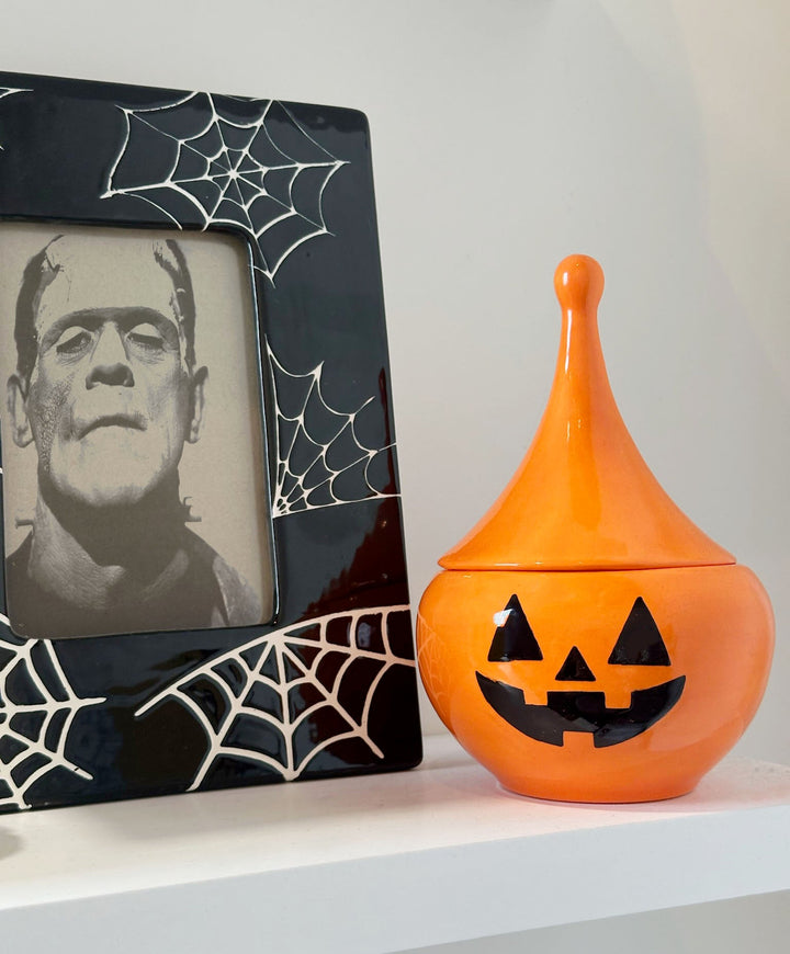 Halloween-themed decorative item with Frankenstein's monster picture and orange jack-o'-lantern container.