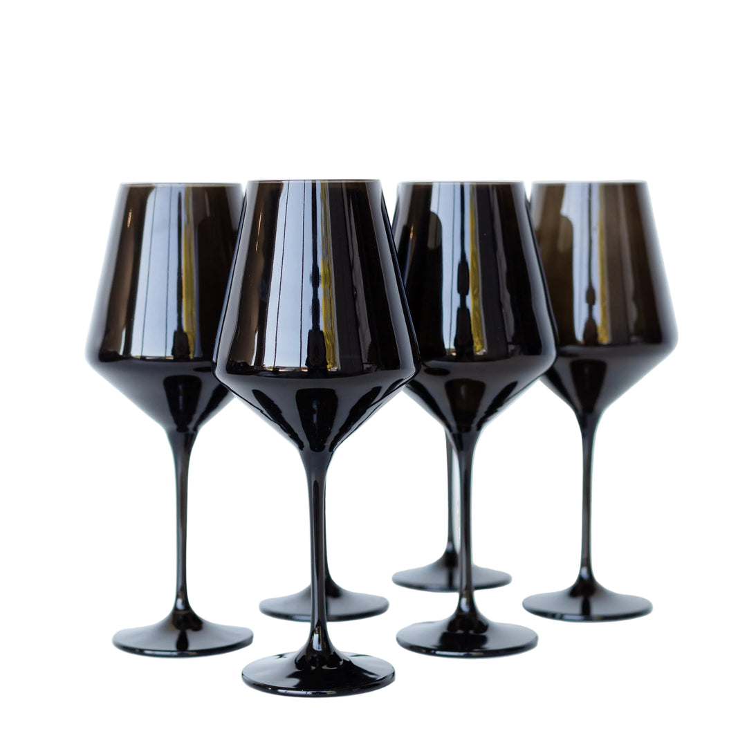Four black wine glasses on a white background