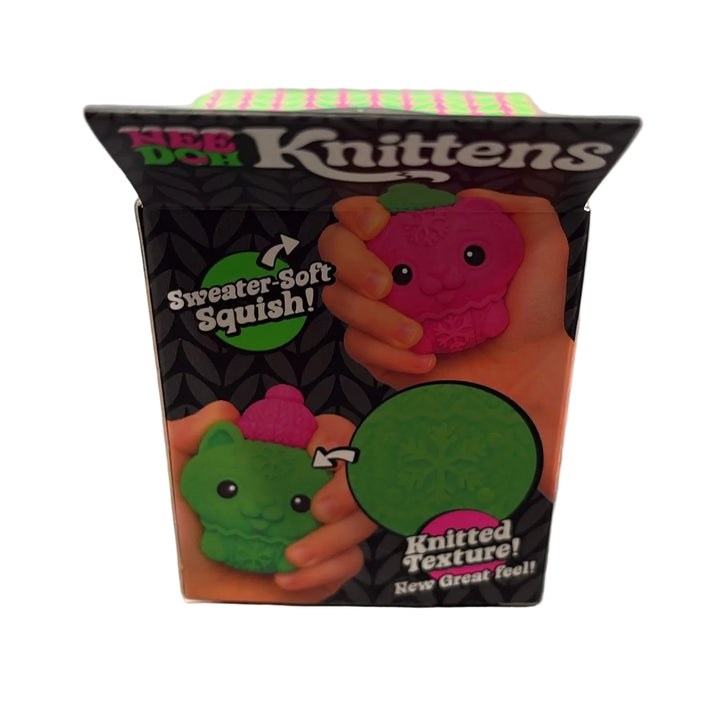 A boxed novelty toy called '100 Don Knittens' standing upright on a gray countertop. The package shows cartoon fruit-like characters in pink and green with text including 'Sweater-Soft Squishy!' and 'Knitted Texture!'.
