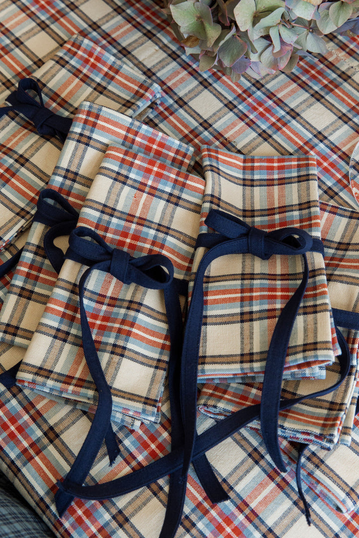 Laurel plaid cloth napkins tied with indigo ribbon on a matching plaid tablecloth
